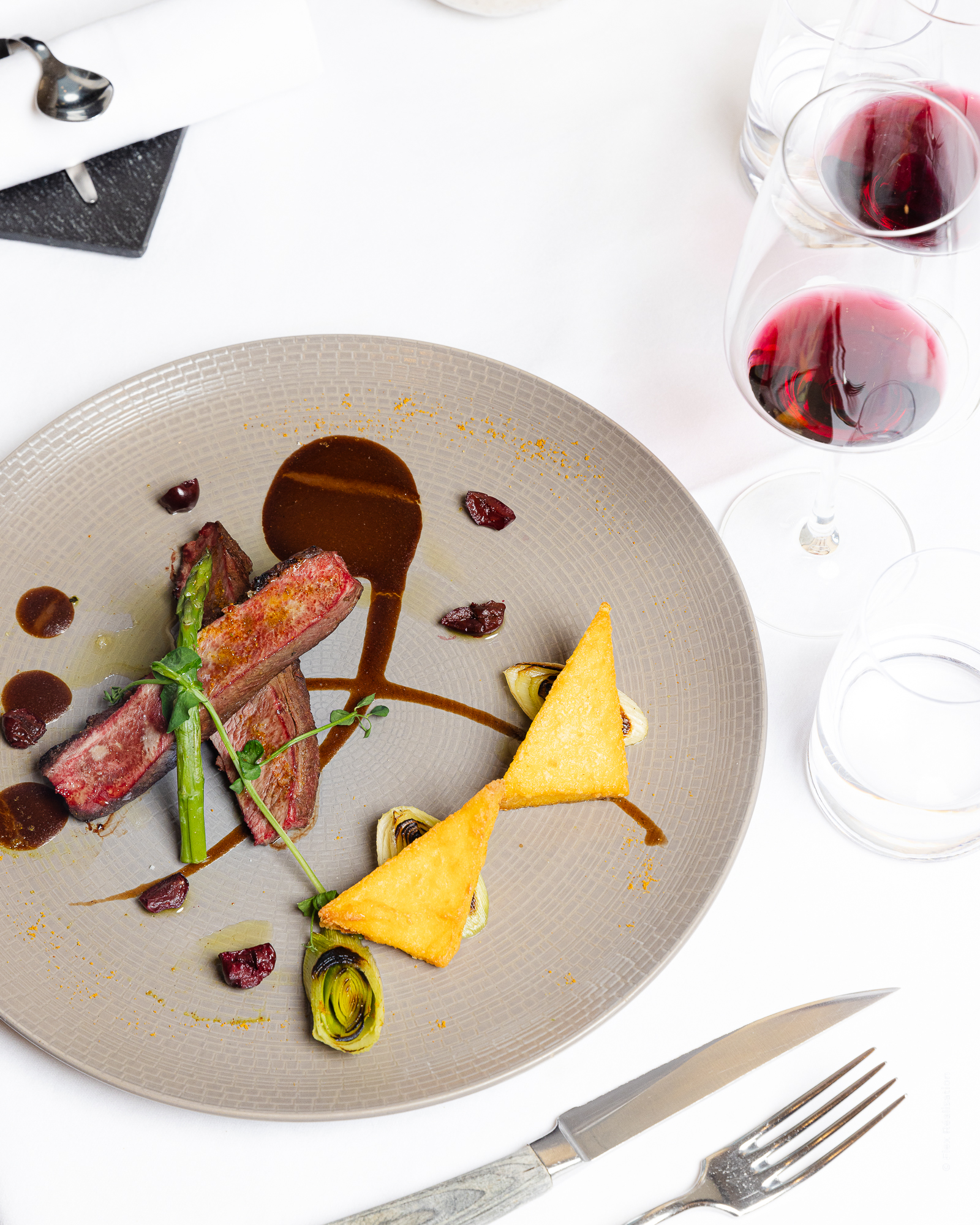 Elegant glass of red wine placed on a green table with dim ambient lighting.