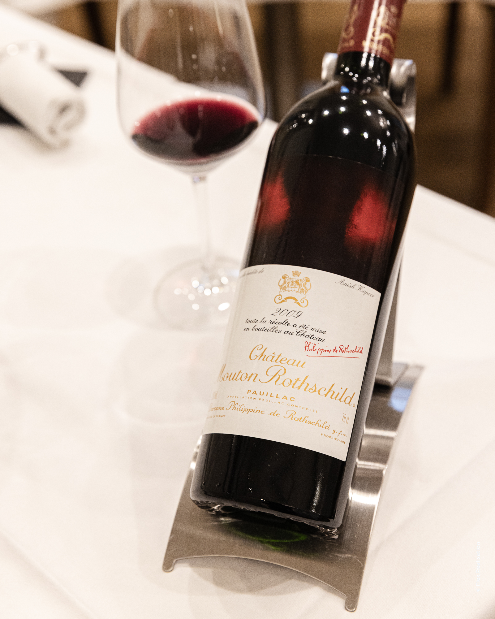 Elegant glass of red wine placed on a green table with dim ambient lighting.